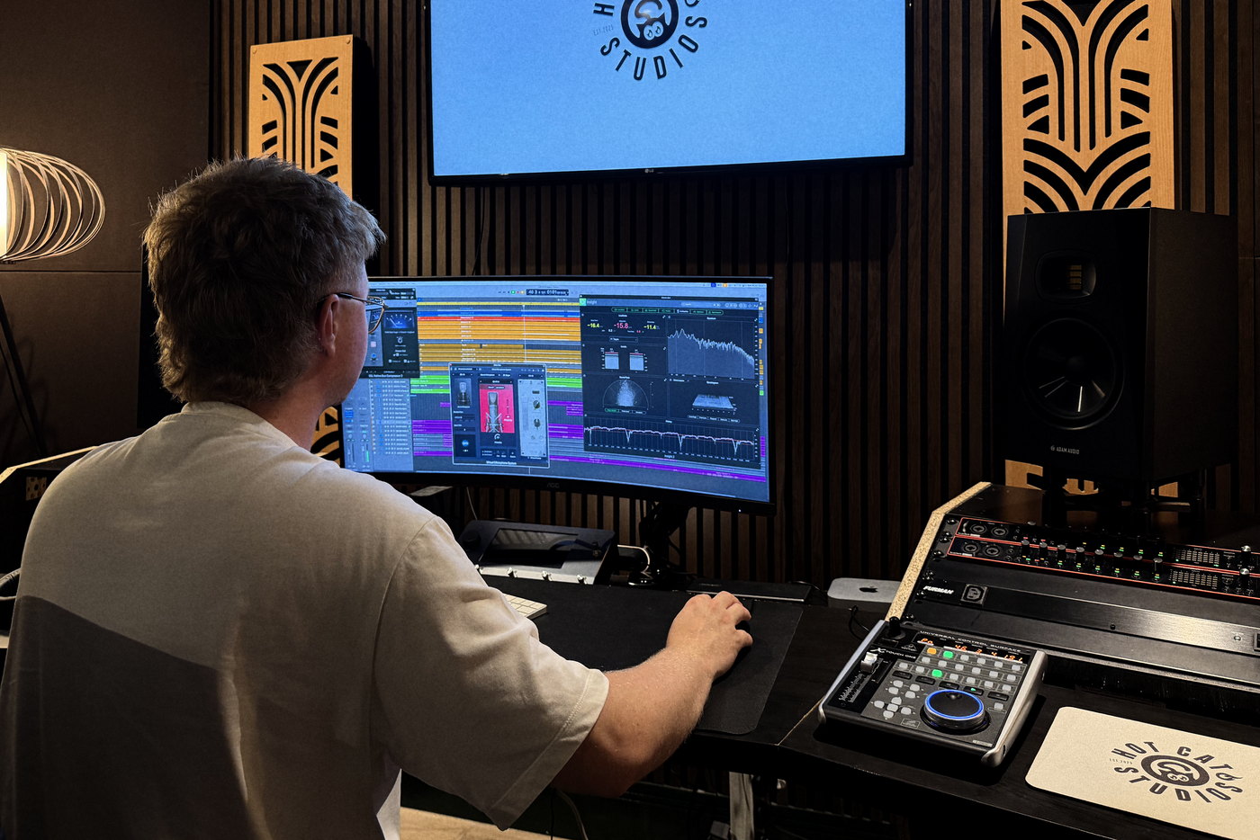 An engineer at the mixing desk in the Hot Cat Studios control room, a session open across the monitor.