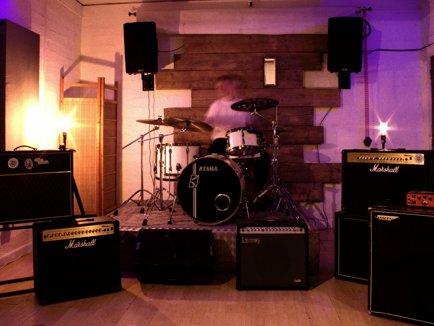 The live room at Hot Cat Studios: drum kit on the riser against a reclaimed timber wall, guitar and bass backline either side.